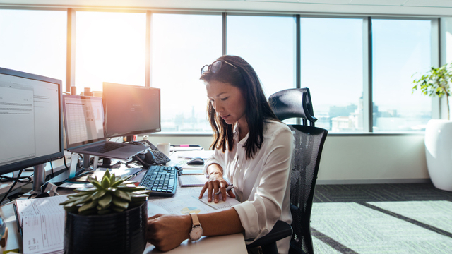 woman sitting at desk reading paper