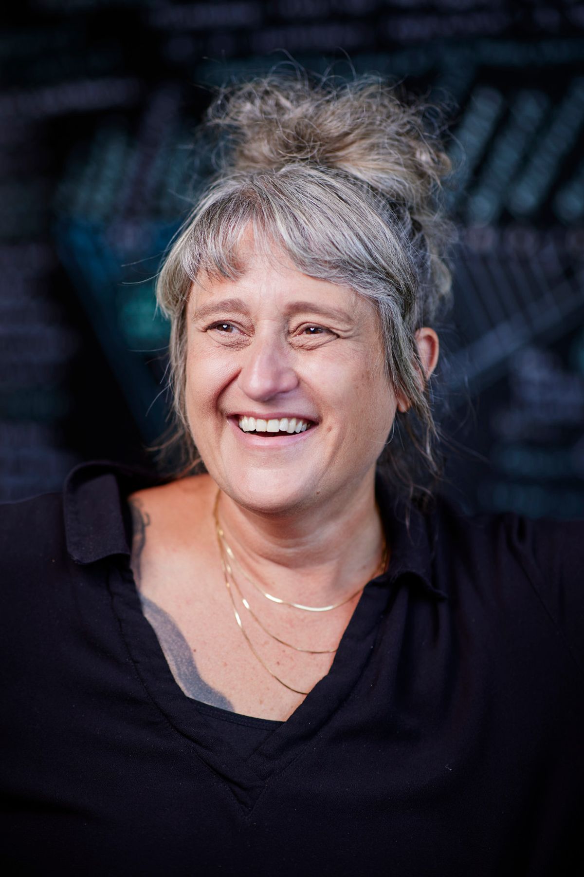 headshot of Gül Dölen smiling with gray hair pulled up on top of head