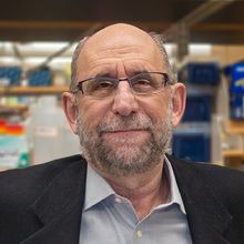 Michael Green smiling at the camera in front of a shelf in the lab