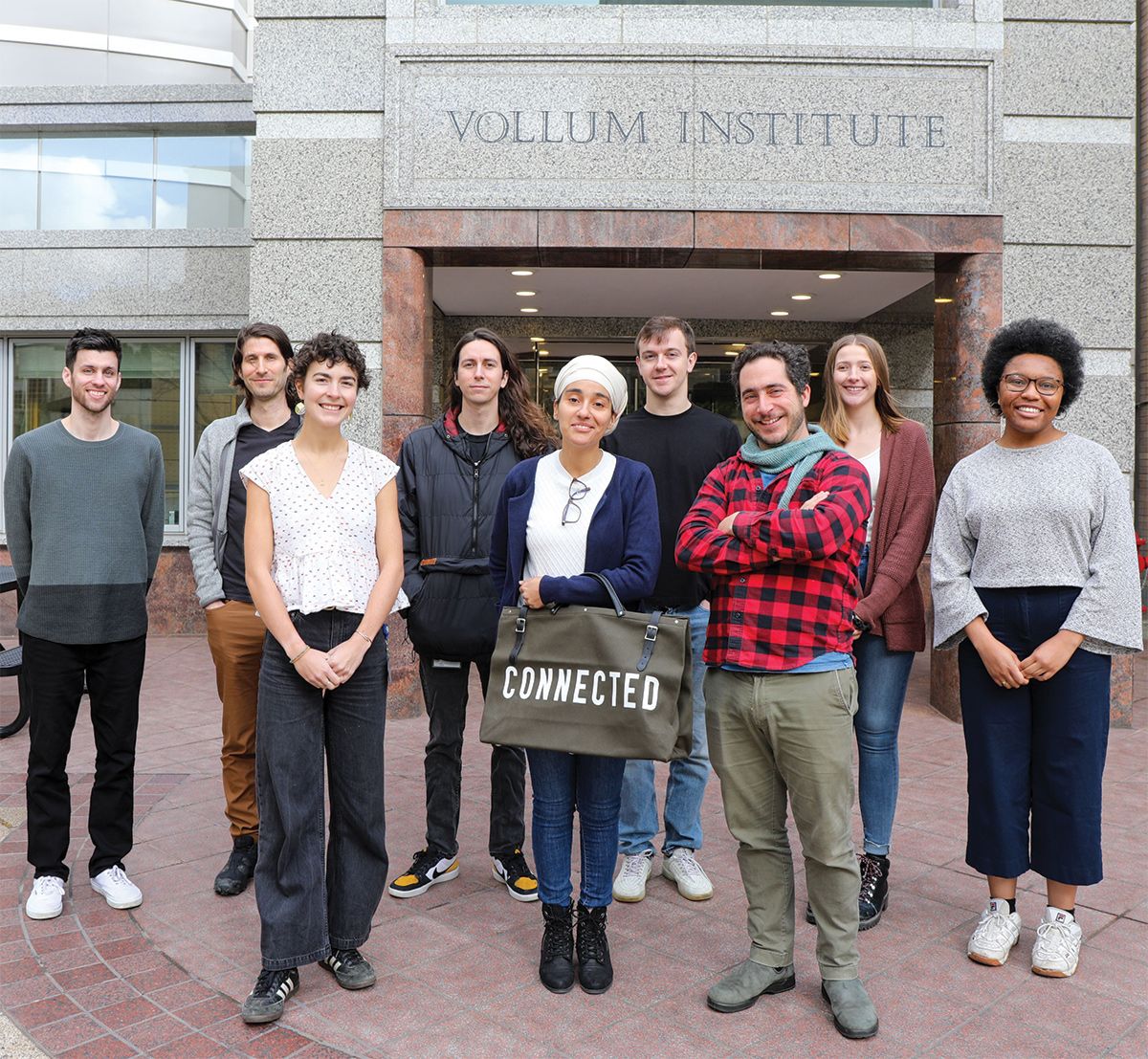 A group of researchers stand outside a building labelled the Vollum Institute.