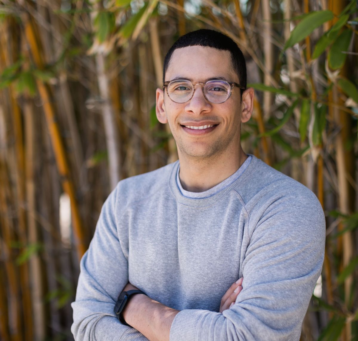 Ahmed Badran wears a grey sweater and smiles at the camera with his arms crossed.