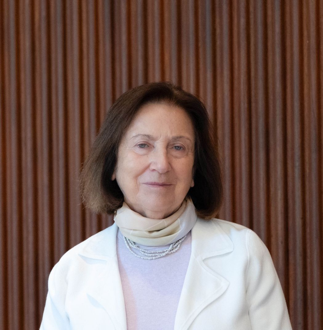 Photo of Breakthrough Prize laureate, chemist Svetlana Mojsov against a brown background. She wears a violet top and white jacket and smiles. Photo of Breakthrough Prize laureate, chemist Svetlana Mojsov against a brown background. She wears a violet top and white jacket and smiles.