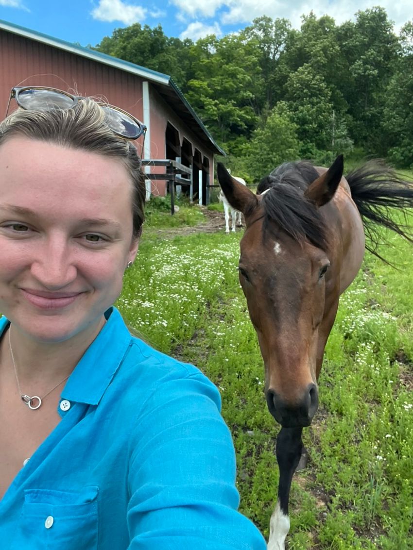 picture of Megan Fahey in a blue shirt next to a brown horse. picture of Megan Fahey in a blue shirt next to a brown horse.