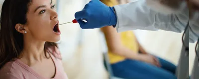 Doctor taking throat swab test from young female patient in the medical clinic. 