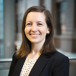 A photo of Hannah Pletcher. She wears a beige top, black blazer, and smiles at the camera. A photo of Hannah Pletcher. She wears a beige top, black blazer, and smiles at the camera.