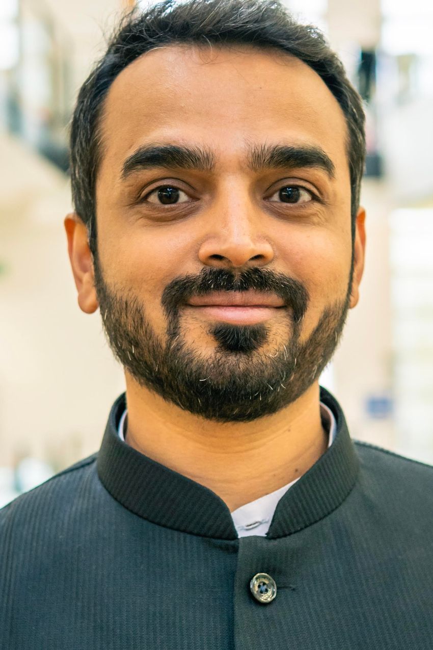 Image of Drupad Trivedi, wearing a dark striped shirt, on a blurred off-white background Image of Drupad Trivedi, wearing a dark striped shirt, on a blurred off-white background