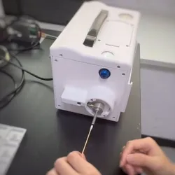 A person’s left hand holding cotton bud in front of a tabletop equipment.