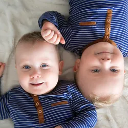 Identical twins lying upside down on white blanket.
