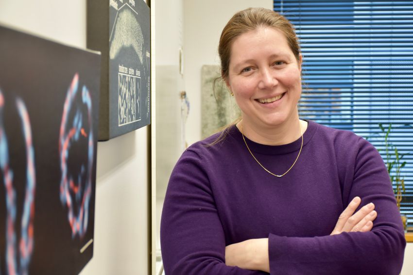 Image of Monica Colaiácovo. She smiles at the camera and is wearing a purple sweater.