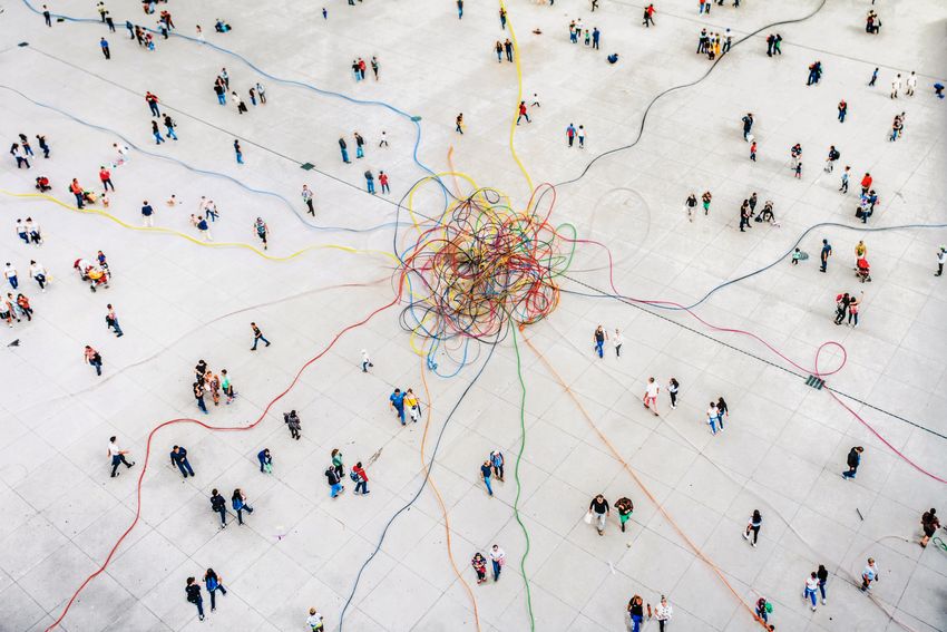 Aerial view image of people around jumbled, colorful threads.