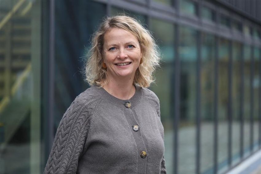 Image of Sine Hadrup, wearing a gray cardigan, in front of a blurred background of a building. Image of Sine Hadrup, wearing a gray cardigan, in front of a blurred background of a building.