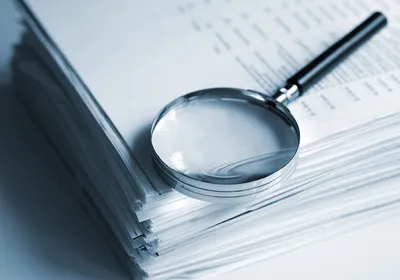 Magnifying glass on a stack of documents.