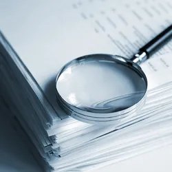 Magnifying glass on a stack of documents. Magnifying glass on a stack of documents.