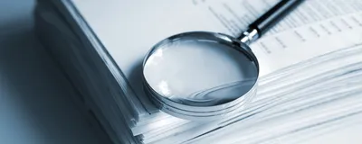 Magnifying glass on a stack of documents.
