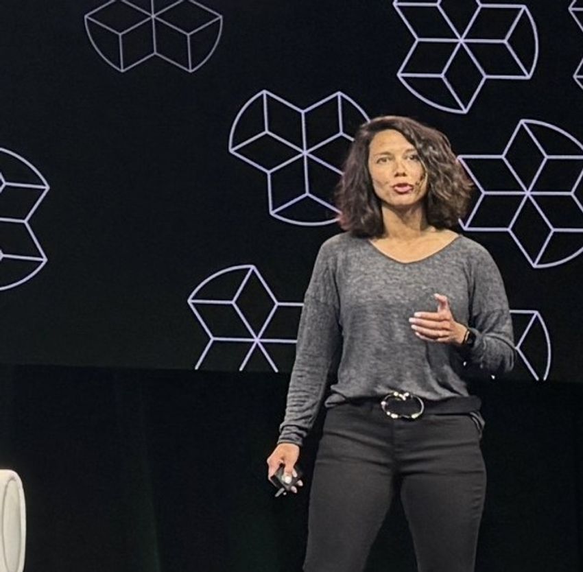 Elizabeth Bennett speaks in front of a black background with geometric shapes. Elizabeth Bennett speaks in front of a black background with geometric shapes.