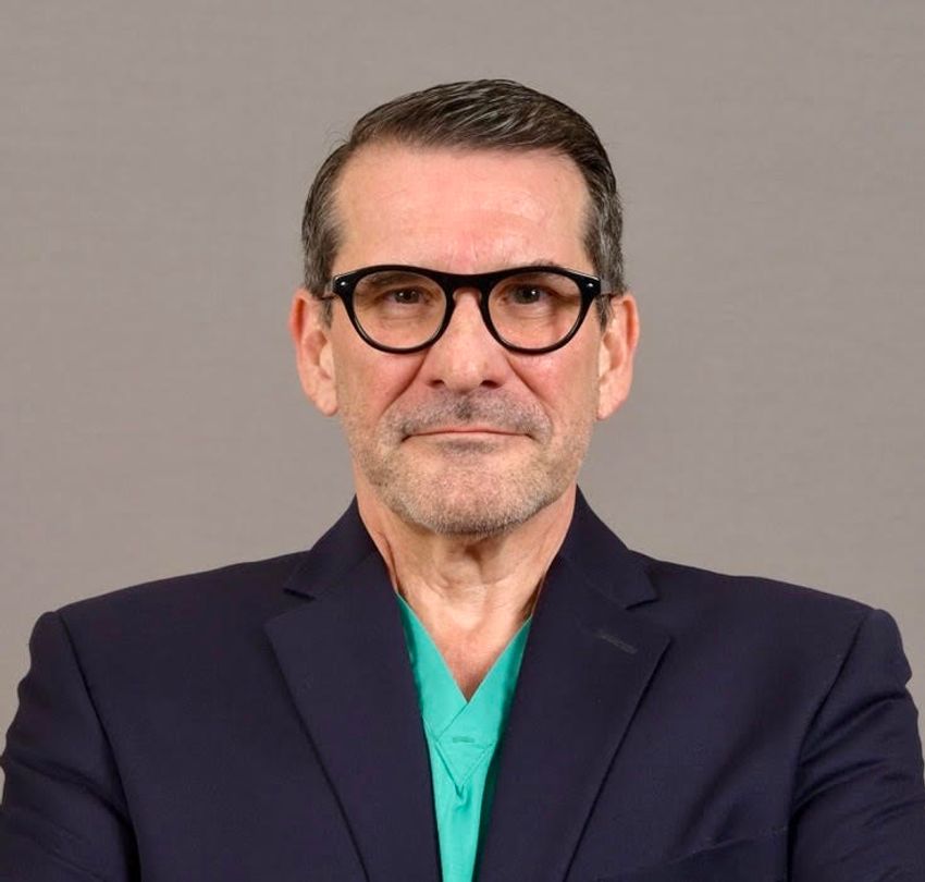 Image of Gustavo Ayala, wearing glasses and teal scrubs under a navy suit, on a light grey background. Image of Gustavo Ayala, wearing glasses and teal scrubs under a navy suit, on a light grey background.