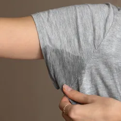 Image of a person in a gray shirt with a sweat stain in the armpit area of their shirt. Image of a person in a gray shirt with a sweat stain in the armpit area of their shirt.