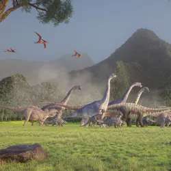 Multiple dinosaurs walk across a lush valley landscape. Several pterosaur-like creatures roam the sky, and two trees frame the image, as a hill looms in the background. Multiple dinosaurs walk across a lush valley landscape. Several pterosaur-like creatures roam the sky, and two trees frame the image, as a hill looms in the background.
