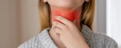A girl holds her throat with her left hand. The region where the vocal cords would be is glowing red, indicating some strain, or even voice box cancer, which an AI-based tool may help detect. 