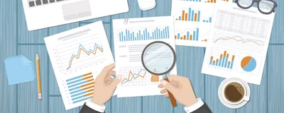 Top view of office space shows hands on the desktop holding a tablet and charts, diagrams, graphs on a surrounding paper, indicating preparation for grant submission.