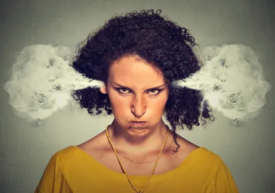 A closeup picture of an angry woman, with steam blowing out of her ears. She wears a yellow top and growls at the camera. A closeup picture of an angry woman, with steam blowing out of her ears. She wears a yellow top and growls at the camera.