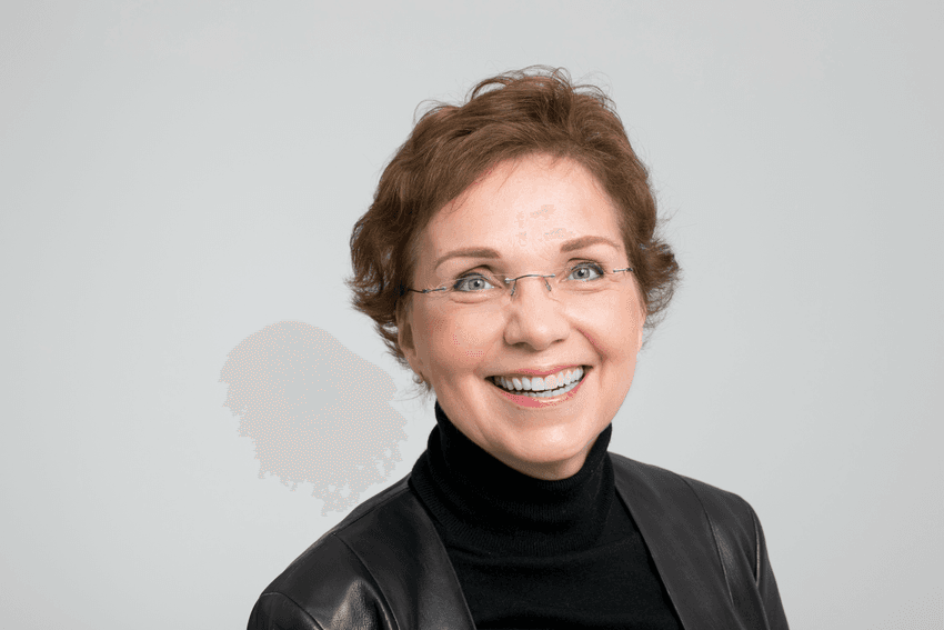 Petra Arck, who studies fetal microchimerism, wears a black turtleneck and smiles against a white background.