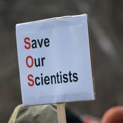A paper protest sign reads “Save Our Scientists”, signifying the crisis that US scientists are facing due to severe federal research funding cuts. A paper protest sign reads “Save Our Scientists”, signifying the crisis that US scientists are facing due to severe federal research funding cuts.