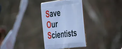 A paper protest sign reads “Save Our Scientists”, signifying the crisis that US scientists are facing due to severe federal research funding cuts. A paper protest sign reads “Save Our Scientists”, signifying the crisis that US scientists are facing due to severe federal research funding cuts.