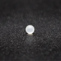 A fat-absorbing microbead, white and pearl-like, lies on a black speckled surface.