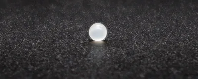 A fat-absorbing microbead, white and pearl-like, lies on a black speckled surface.