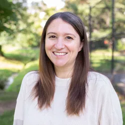 Laura Dattaro wears a white sweater in front of trees. Laura Dattaro wears a white sweater in front of trees.