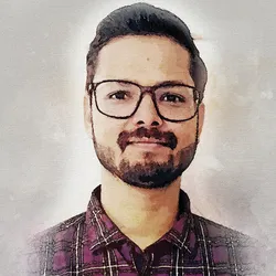Dhruvam Pandey, a postdoctoral researcher at The College of Optics and Photonics, wears a plaid shirt and smiles gently at the camera.