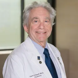 A photograph of Charles Nemeroff wearing a blue shirt, striped blue tie, and white lab coat.