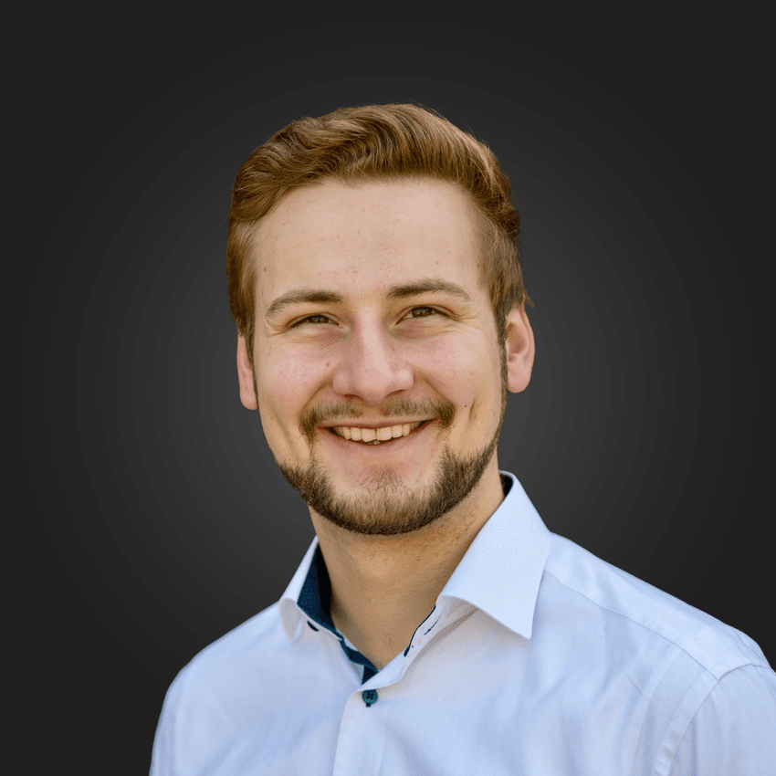 Sebastian Oehm is smiling, wearing a white shirt against a grey background