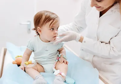 A health care professional assessing a baby, highlighting the importance of addressing early childhood health. A health care professional assessing a baby, highlighting the importance of addressing early childhood health.