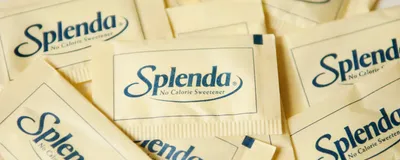 Light yellow packets of Splenda, a common trade name for sucralose and the artificial sweetener recently found to worsen response to cancer immunotherapy, are strewn all over a white surface Light yellow packets of Splenda, a common trade name for sucralose and the artificial sweetener recently found to worsen response to cancer immunotherapy, are strewn all over a white surface