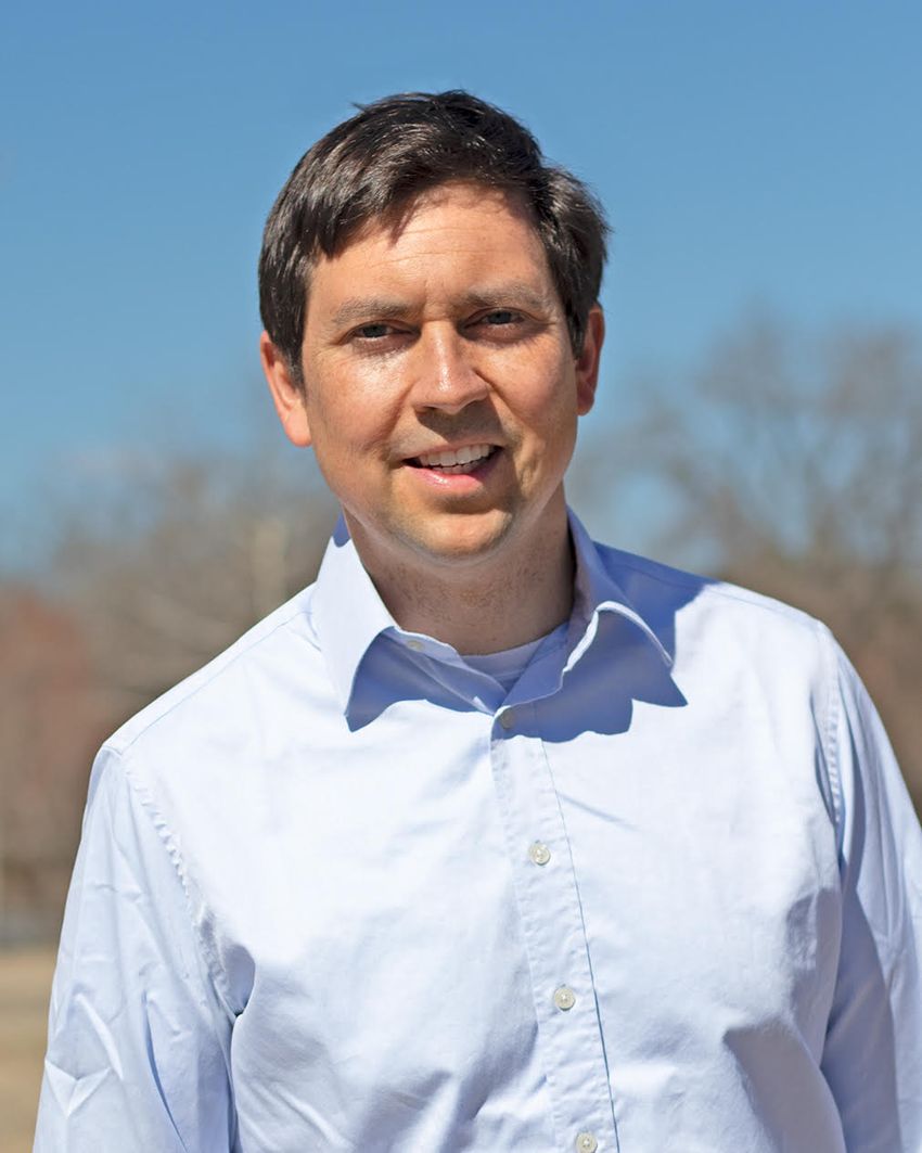 Daniel Forger poses in front of a blurred landscape. He’s wearing a light blue shirt.