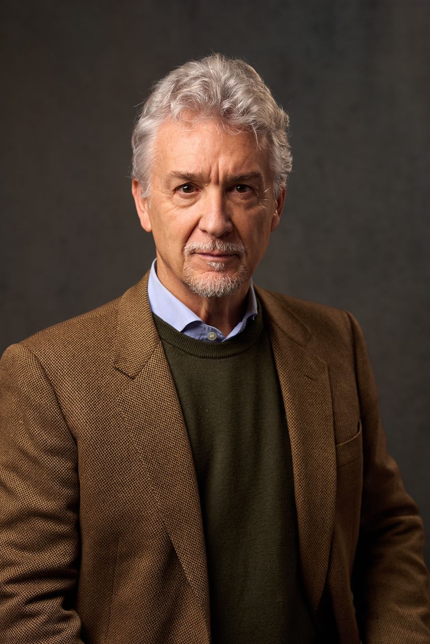 A photo of Stefano Piraino wearing a brown jacket, brown sweater, and blue shirt against a brown background. A photo of Stefano Piraino wearing a brown jacket, brown sweater, and blue shirt against a brown background.