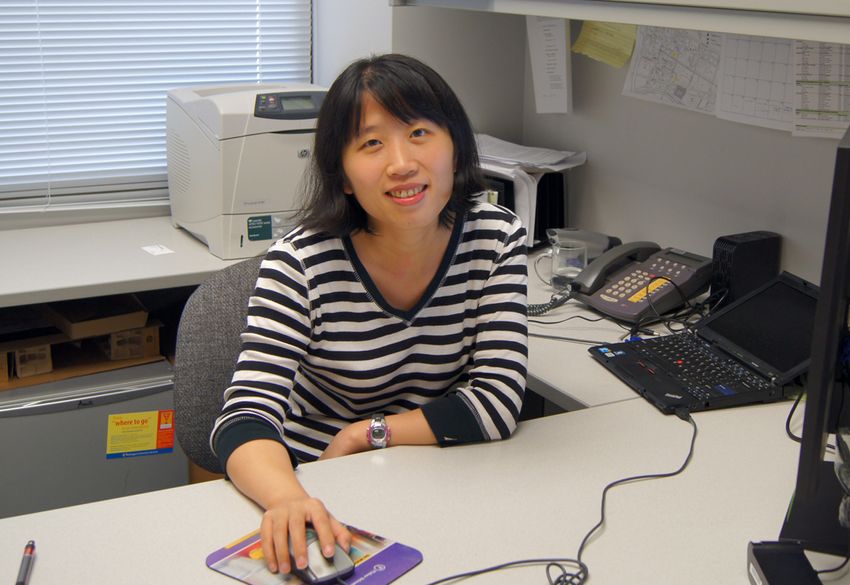 Qin Liu, who studies the neural mechanism of sneezing, wears a striped top and sits at her desk.