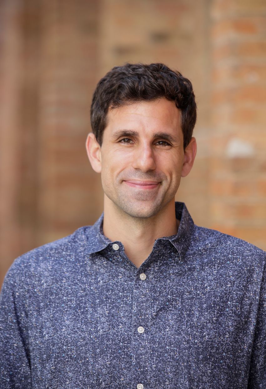 César de la Fuente, a computational biologist at the University of Pennsylvania, wears a blue shirt and stands against a blurred-wall background.