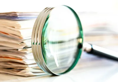 Magnifying glass in front of a stack of documents, signifying that ChatGPT ignored retractions. 