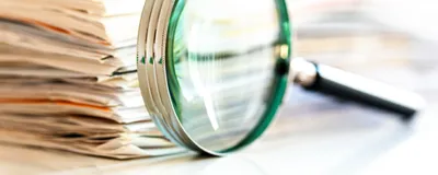 Magnifying glass in front of a stack of documents, signifying that ChatGPT ignored retractions. 