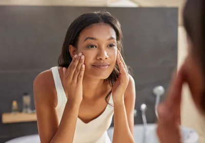 A woman applying cream to her face. The skin stretching in this process could stimulate immune surveillance and open up hair follicles.