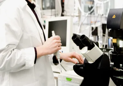 A researcher examining a sample under a confocal microscope in the laboratory. A researcher examining a sample under a confocal microscope in the laboratory.