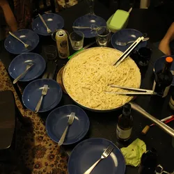 A big bowl of cacio e pepe sits in the center of a table surrounded by empty pasta bowls waiting to be filled. A big bowl of cacio e pepe sits in the center of a table surrounded by empty pasta bowls waiting to be filled.
