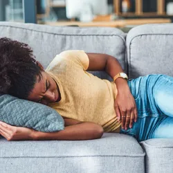 Young woman clutching abdomen in discomfort, showing symptoms of inflammatory bowel disease. Young woman clutching abdomen in discomfort, showing symptoms of inflammatory bowel disease.