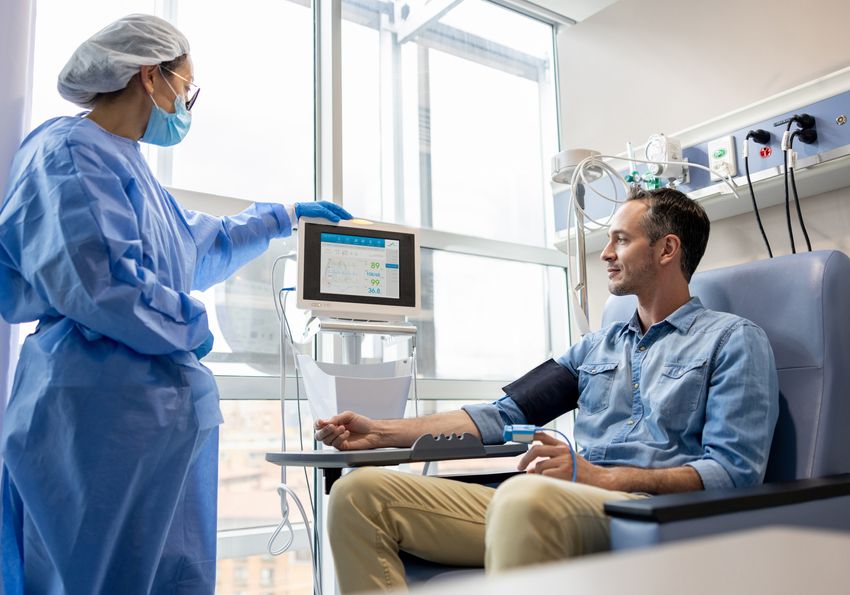 A photo of a patient undergoing immunotherapy for cancer and a medical professional observing their treatment