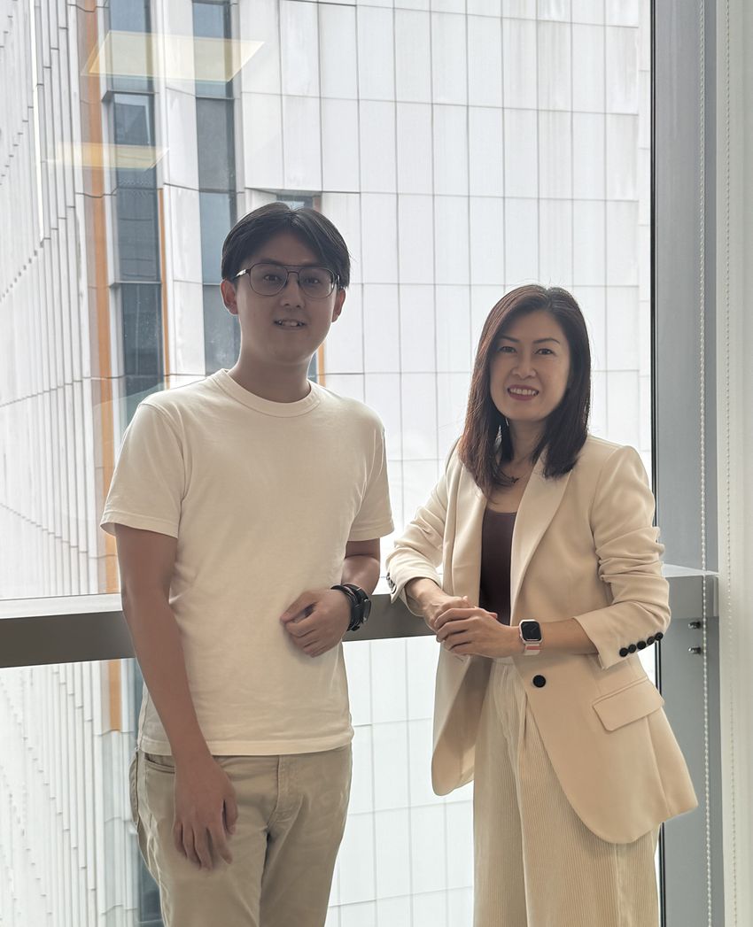 Rachel Ee (right) and her graduate student Wei Meng Chen (left), who led the study, pose inside of a building in front of glass windows. Ee is wearing a matching beige suit, a dark brown top underneath, and a watch. Chen is wearing a white tee, khaki pants, glasses, and a watch.