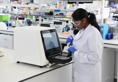 A scientist pipettes a solution into a multi-well plate that sits in Nuclera’s eProtein Discovery System 