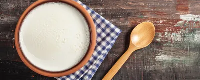 Yogurt in an earthen pot with a wooden spoon by the side. 
